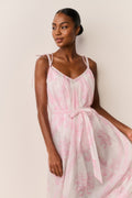 Woman wearing a pink and white patterned dress against a plain background