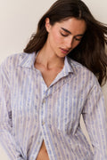 Woman wearing a floral striped button down shirt against a plain background