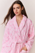 Woman wearing a pink bow print robe against a plain background