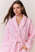 Woman wearing a pink bow print robe against a plain background