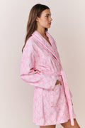 Woman wearing a pink bow print robe against a plain background