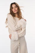 Woman wearing a cream sweater with fluffy sleeves on a white background