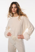 Woman wearing a cream-colored loungewear set on a white background