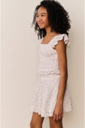 Girl wearing Light pink ruffle sleeve top with floral pattern and matching skirt