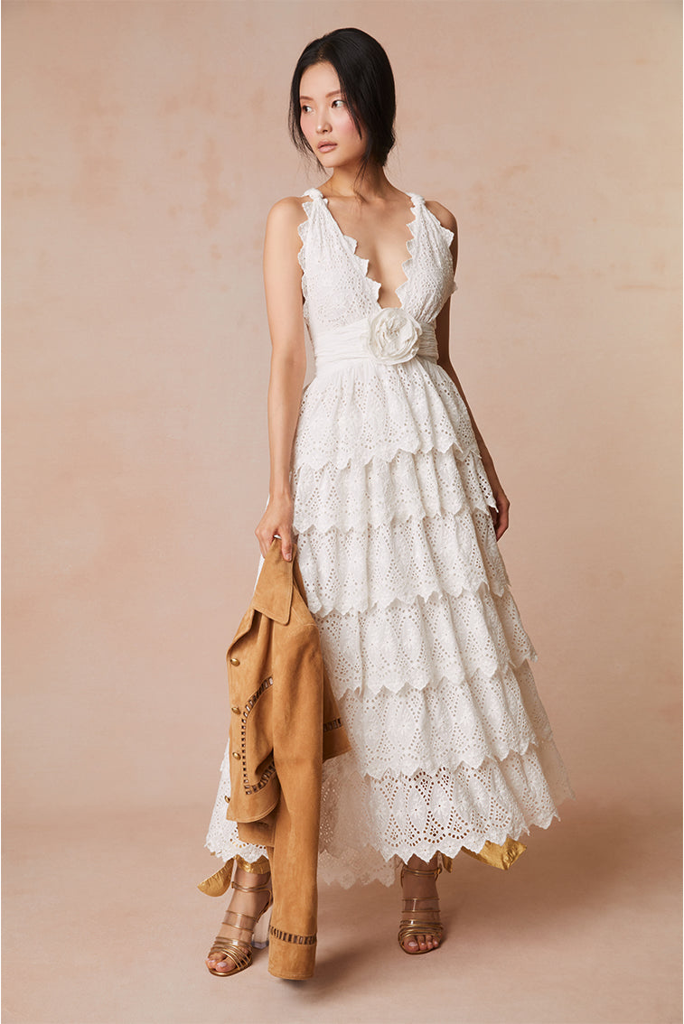 Lace maxi dress with a halter neckline outlined with a scallop edge that criss-crosses in the back. A fabric rosette adorns the center front before falling to the epic, multi-tiered skirt.