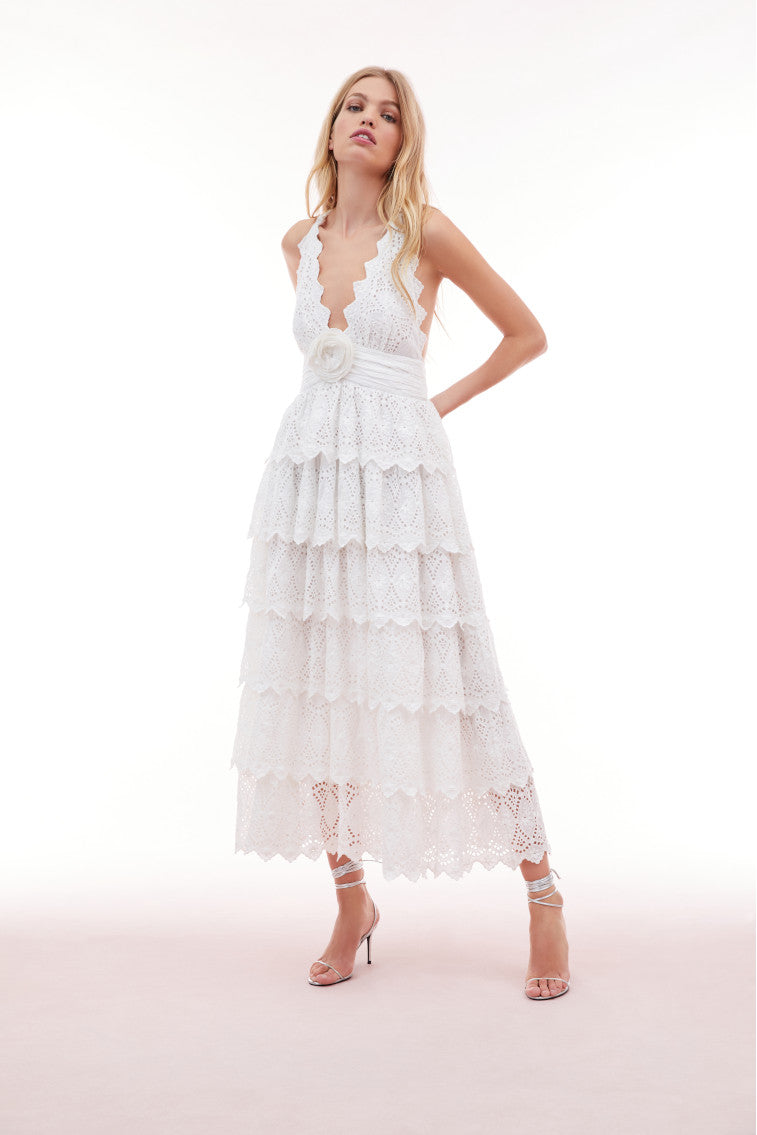 Lace maxi dress with a halter neckline outlined with a scallop edge that criss-crosses in the back. A fabric rosette adorns the center front before falling to the epic, multi-tiered skirt. 
