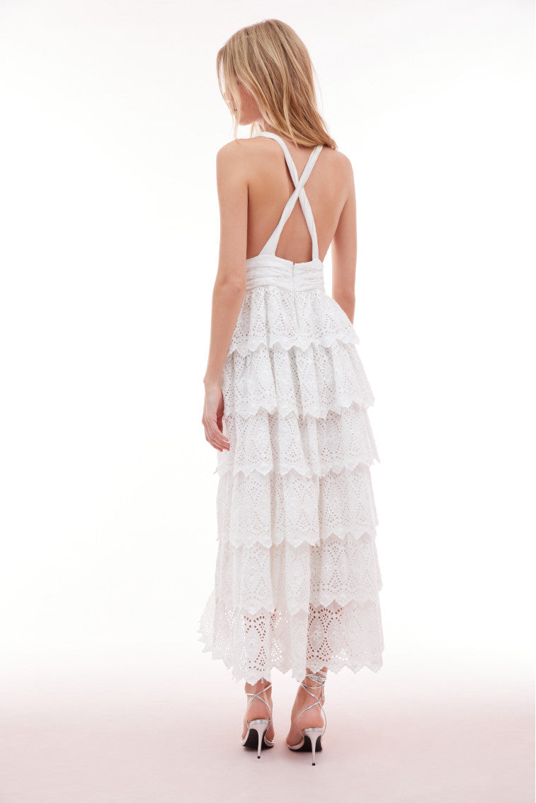Lace maxi dress with a halter neckline outlined with a scallop edge that criss-crosses in the back. A fabric rosette adorns the center front before falling to the epic, multi-tiered skirt.
