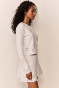 Woman wearing white eyelet trim mini skirt and matching cardigan
