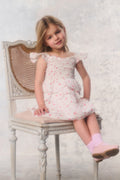 Young girl in a floral dress sitting on a chair with a white textured background