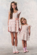 Two young girls wearing matching floral dresses against a light background