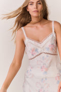 Woman wearing a floral lace satin camisole against a plain background