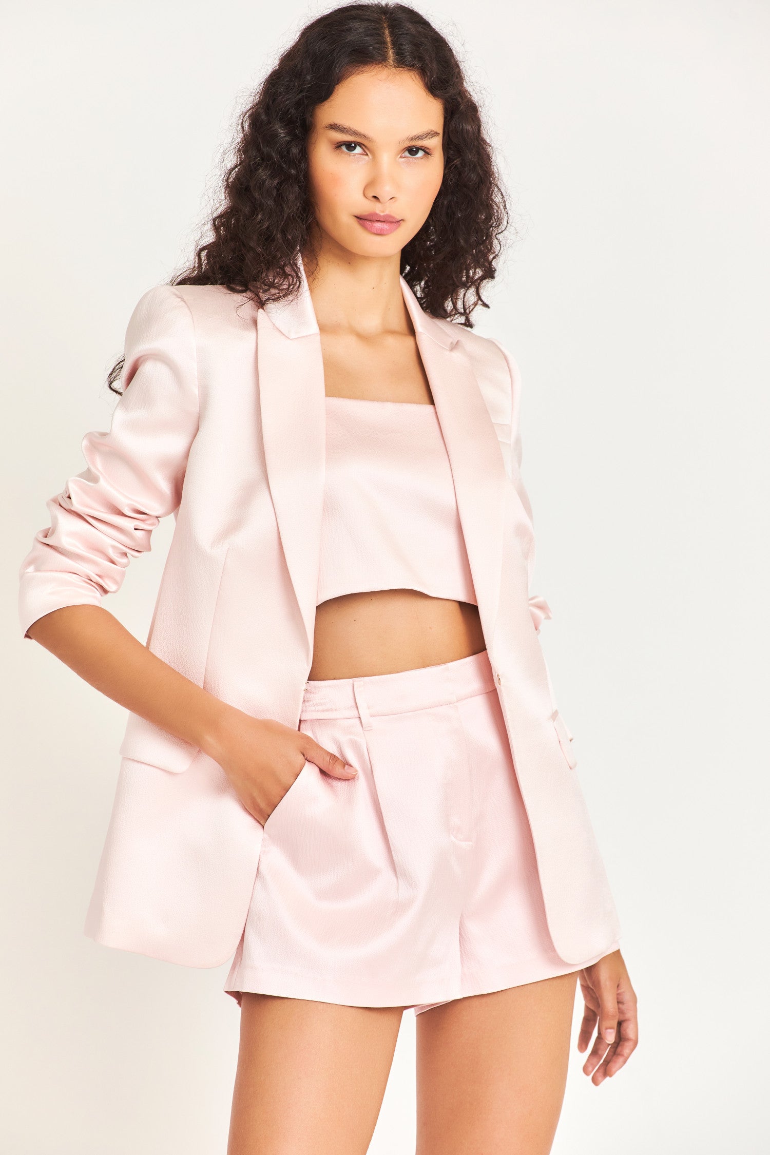 The Gaston Blazer is made of baby pink luxurious silk and has tailoring that gives its structure while featuring a flat pocket, peak lapel, chest pocket, and should pads. 