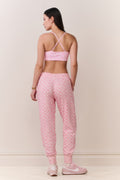 Woman wearing a pink bow print sports bra and matching sweatpants set on a plain background