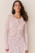 Woman wearing a pink floral cardigan and matching dress against a beige background