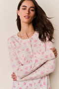Woman wearing a pink floral cardigan and matching dress against a beige background