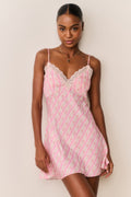 Woman wearing a pink patterned slip dress against a plain background