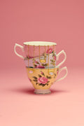 Stack of floral teacups on a pink background