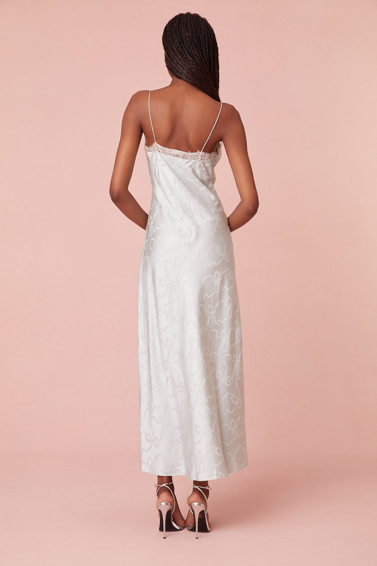 Midi slip dress with jacquard fabric with beautiful bow artwork woven throughout. Features scallop lace detail at the neck, and a subtly sexy cup detail.