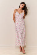 Woman wearing a pink and white floral slip dress against a plain background