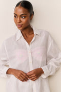 Woman wearing a white button-up shirt against a plain background