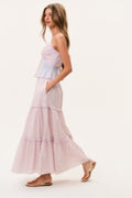 Woman wearing a light pink tiered maxi skirt and matching camisole top on a white background