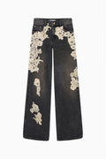 Black wide-leg jeans with cream lace applique along both legs.