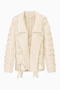 Windel cardigan product shot: ivory textured knit cardigan, open front with shawl collar, ribbon laced through the front, and ribbon bows on the pockets