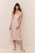 Woman wearing a floral slip dress against a plain background