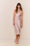 Woman wearing a floral slip dress against a plain background