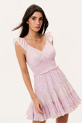 Woman wearing a pink mini dress with ruffled cap sleeves on a white background