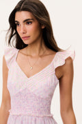 Woman wearing a pink mini dress with ruffled cap sleeves on a white background