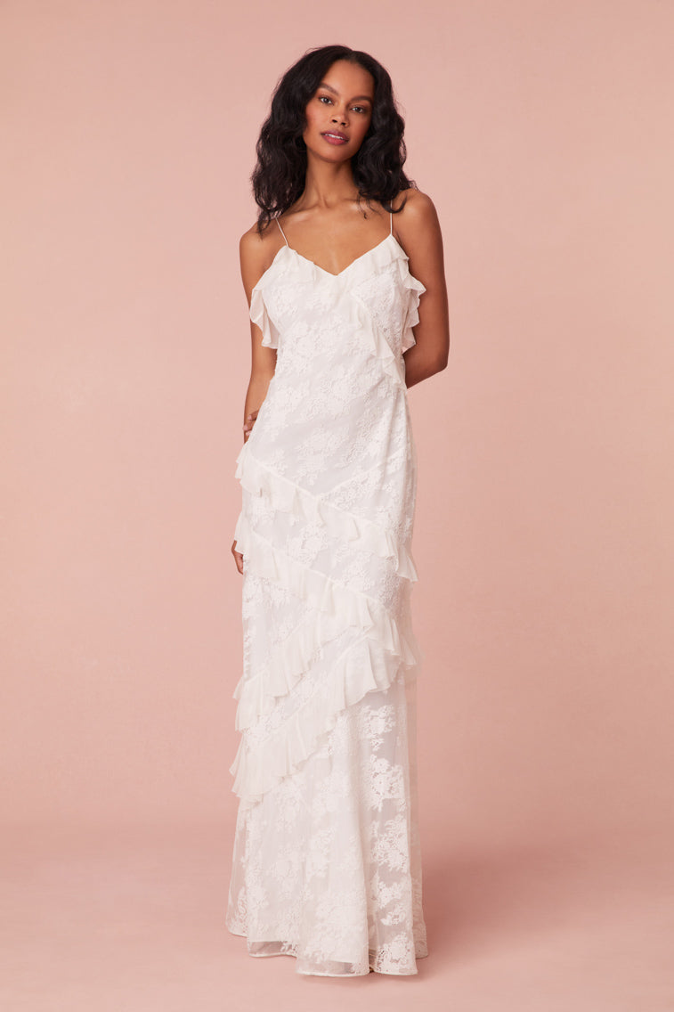 Maxi dress featuring overlapping, asymmetrical ruffles at the neckline that descend through the skirt. Slightly fitted, the dress includes a side seam zipper for closure.