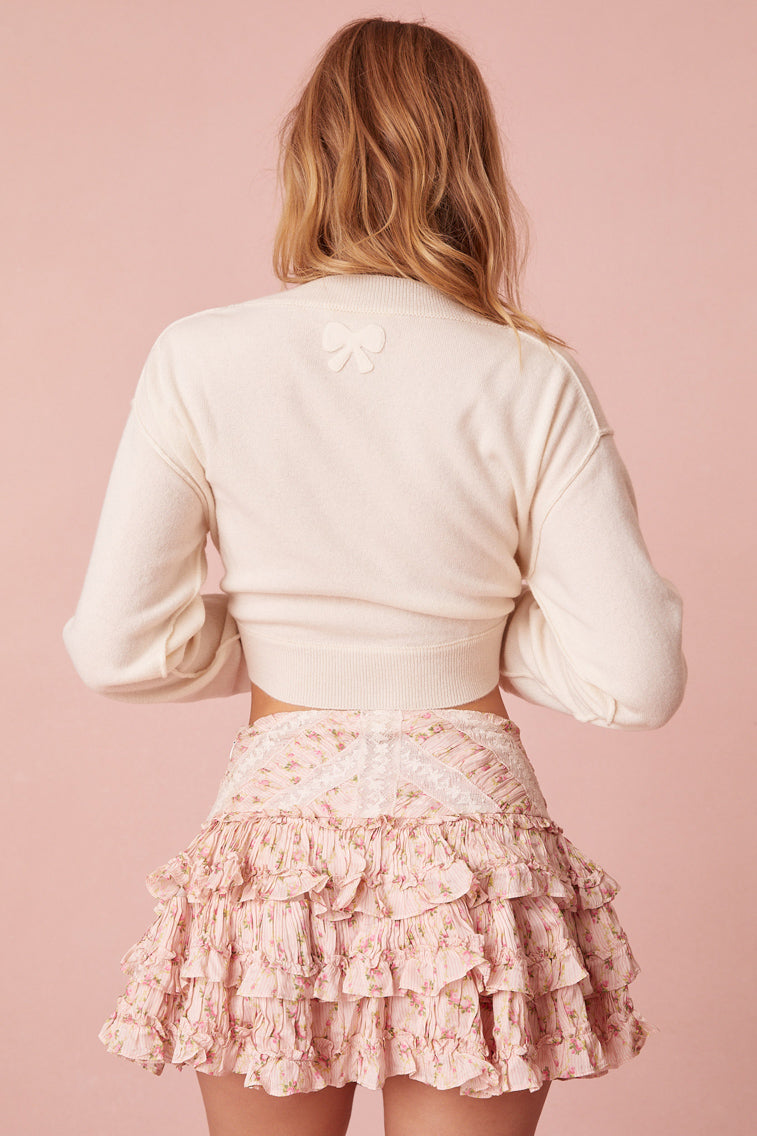 Mini skirt with a fixed waist and pleated ruffle tiers. Shirring details and laces are woven throughout. The piece is finished with a side seam zipper.