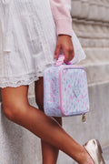 Person holding a floral-patterned lunchbox with the name 'Scarlett" Monogramed on a blurred background