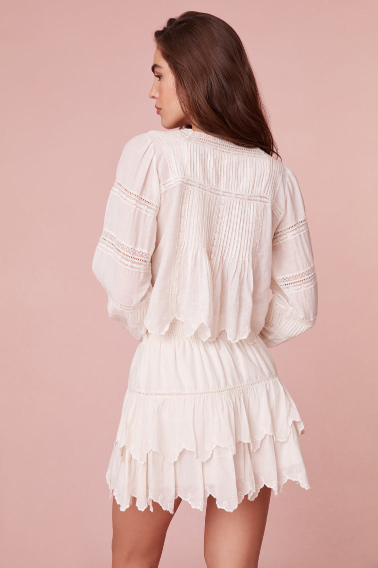Short blouse featuring embroidered scallop with a charming flower.