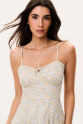 Woman wearing a floral mini dress with thin straps on a plain background