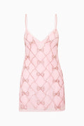 Pink lace mini dress with bow pattern embellishments on a white background