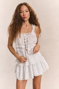 Woman wears white embroidered cotton sleeveless top and matching mini skirt