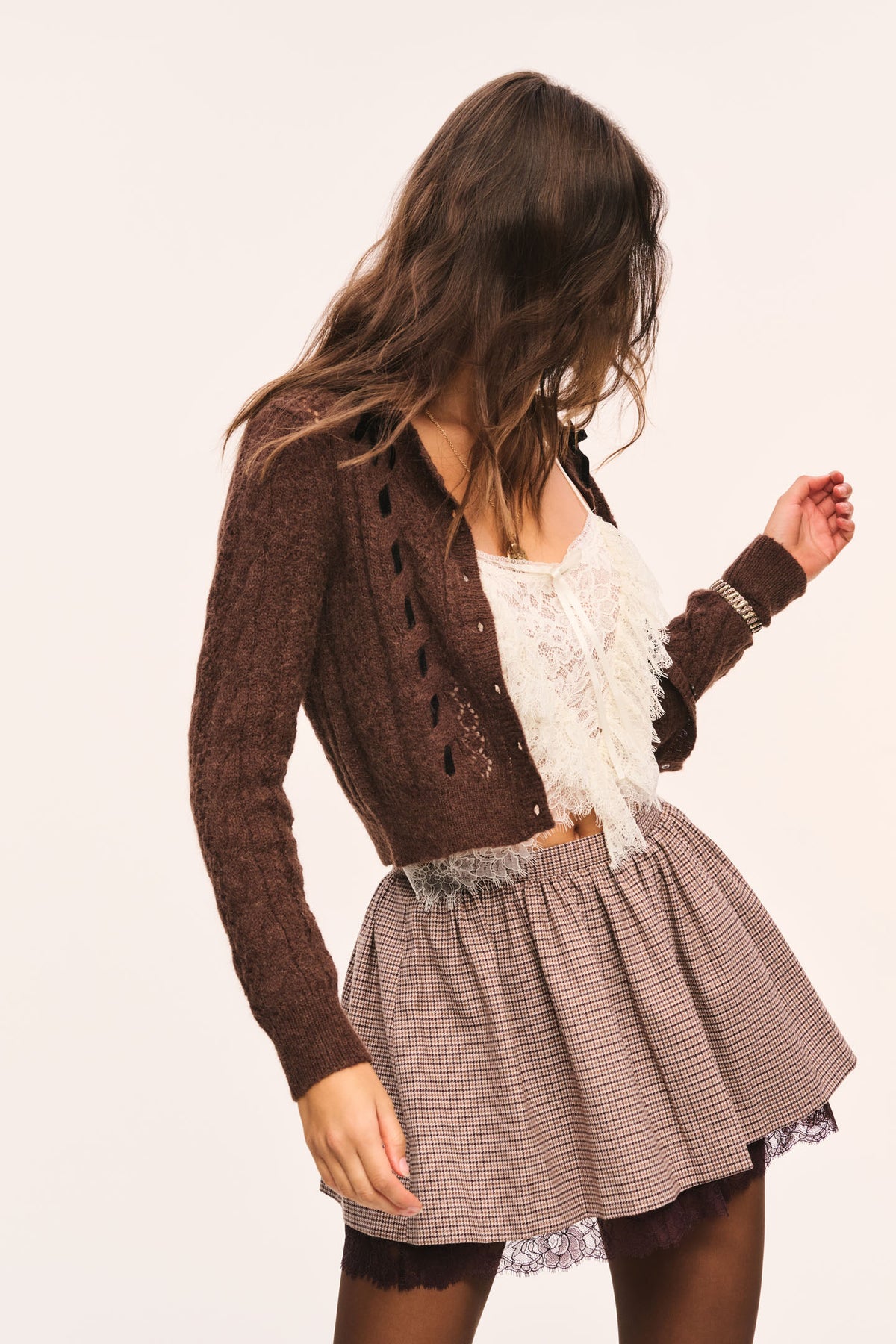 Brown and beige plaid mini skirt with gathered waist and brown lace under layer visible at the hem, front view and model is looking away