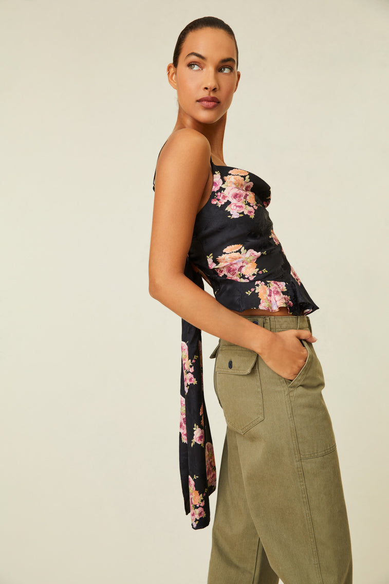 Model is wearing a black floral tank top with ruffled hem and cowl neck