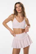 Woman wearing a pink sports bra and skirt on a white background