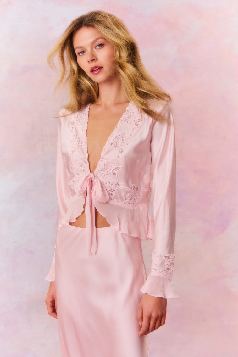 Long bell sleeve top with sheer embroidery and intricate thread work with tiny rhinestones for added shimmer. This blouse features ruffles at the peplum openings, a deep v-neckline with a tie detail at center front, and a peplum hem.
