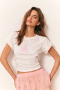 Woman wearing a white t-shirt with a pink logo and a pink skirt on a light background