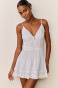 Woman wearing a light blue floral dress against a plain background