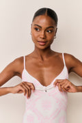 Woman wearing a pink swimsuit with thin straps against a beige background