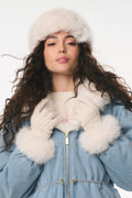 Woman wearing a blue coat with white fur trim, white gloves, and a white fur hat on a white background
