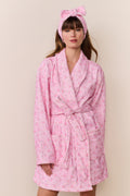 Woman wearing a pink robe and headband with a subtle pattern on a beige background