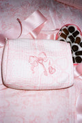 Pink cosmetic pouch with embroidered design on a pink floral background