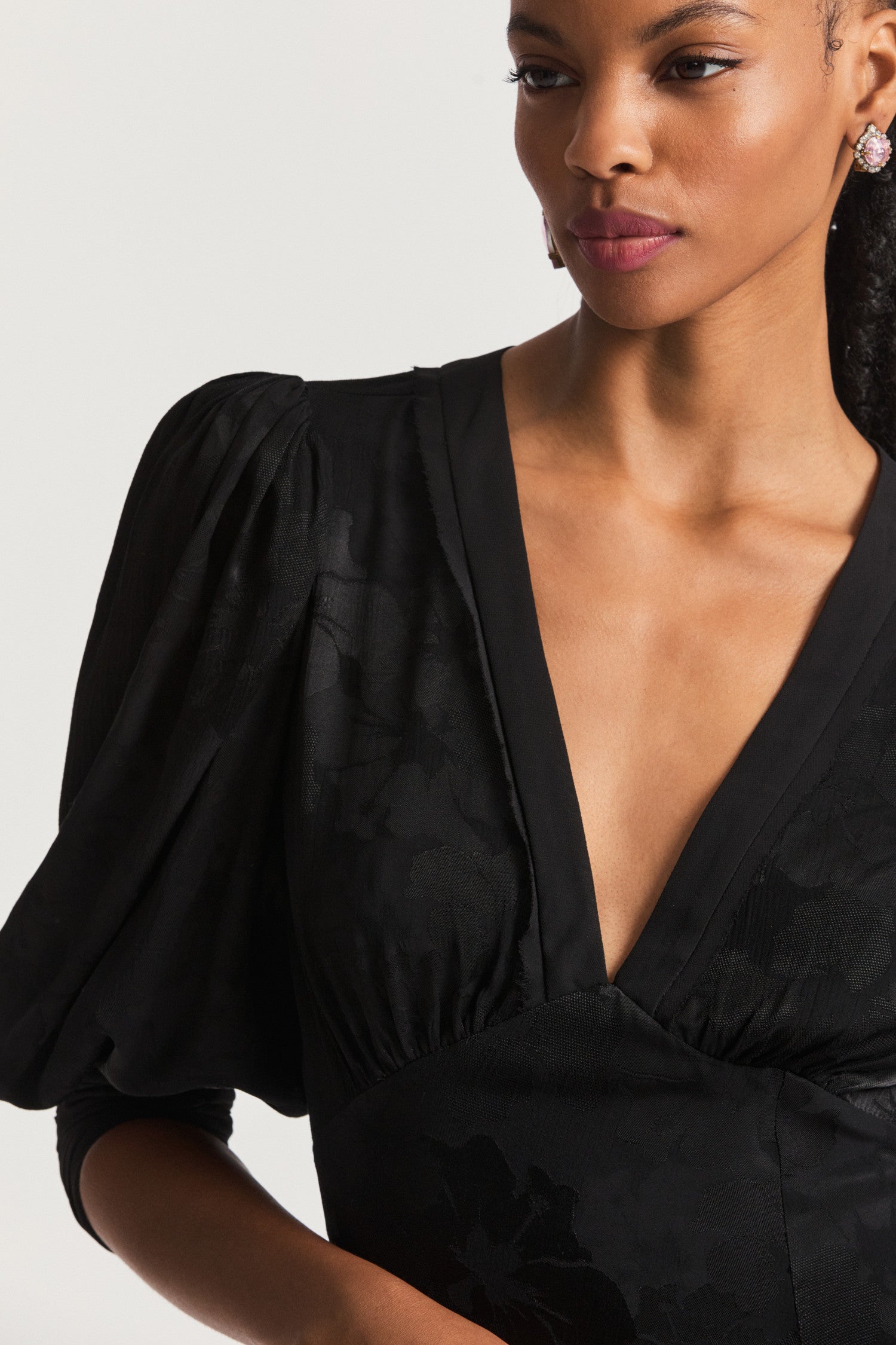 Black Mini Dress with a combination of charmeuse and chiffon. Blouson sleeves, a deep v that falls to a flattering slim fit waist which releases into a princess skirt with tiered pretty ruffle detail at the hem. 