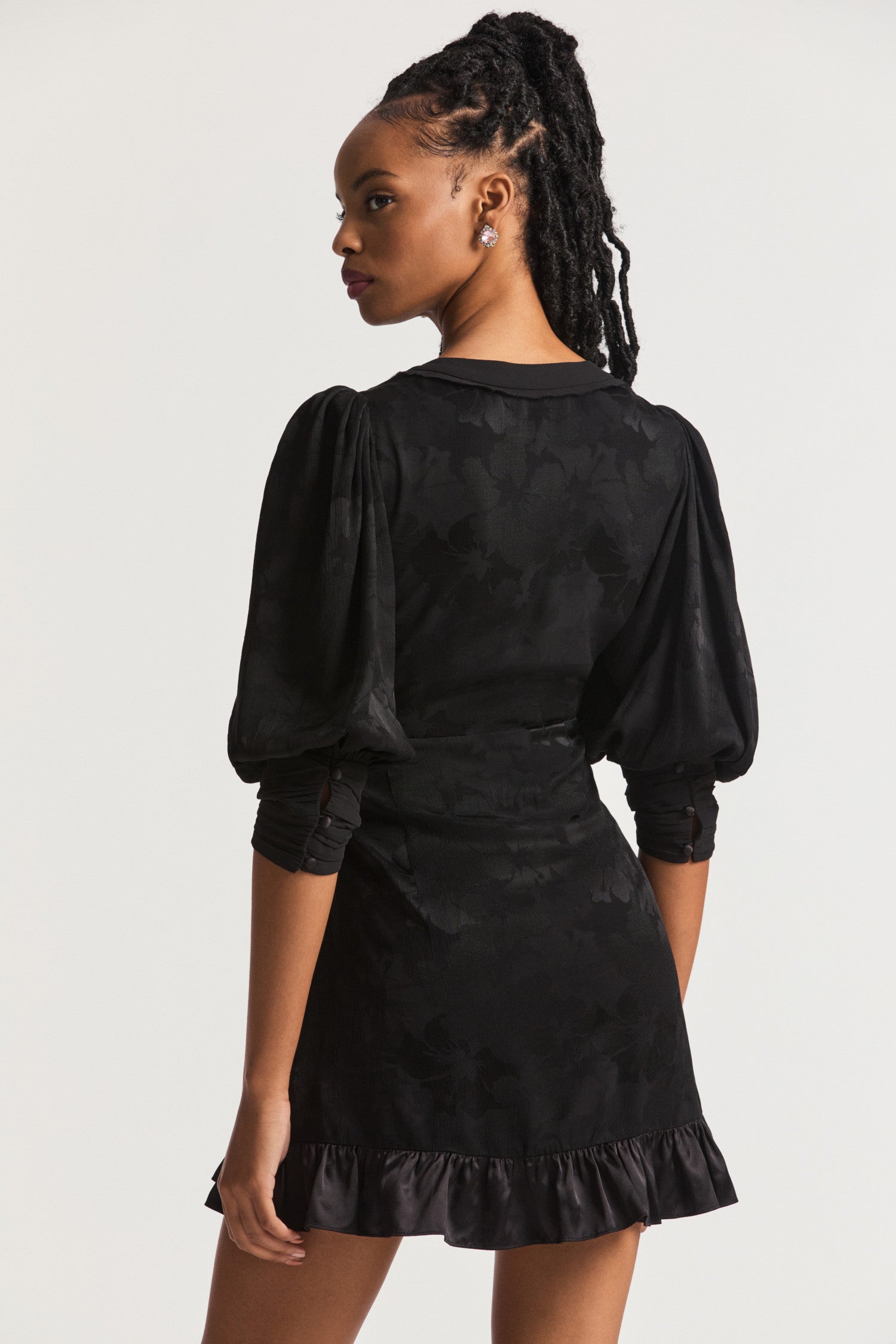Black Mini Dress with a combination of charmeuse and chiffon. Blouson sleeves, a deep v that falls to a flattering slim fit waist which releases into a princess skirt with tiered pretty ruffle detail at the hem. 